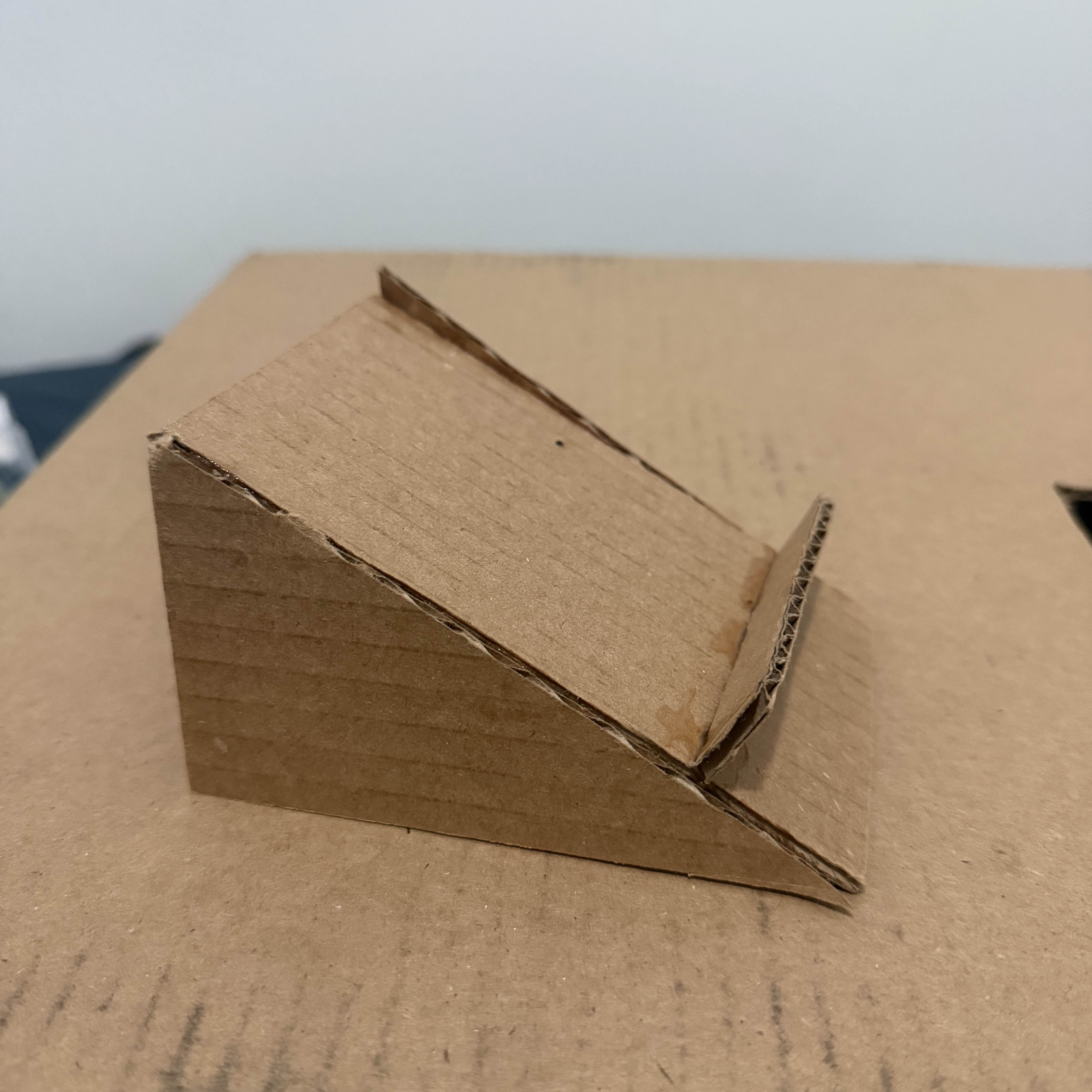 Side view of the folded cardboard stand after cutting and assembling the basic triangular structure.